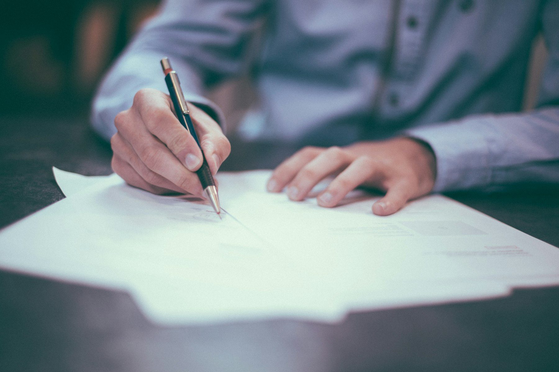 Person signing documents at a desk, comparing pre-settlement funding with a personal loan